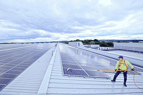 A Leadec employee cleaning the photovoltaic system on a factory roof.