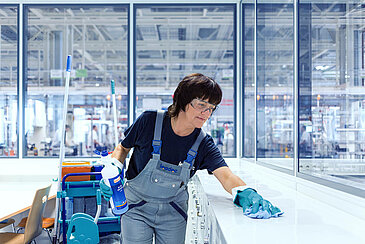 A female Leadec employee cleaning the recreation room in a factory.