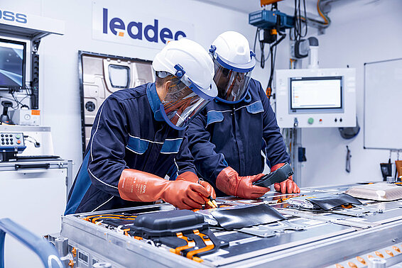 Two Leadec employees in protective clothing repairing a defective battery.